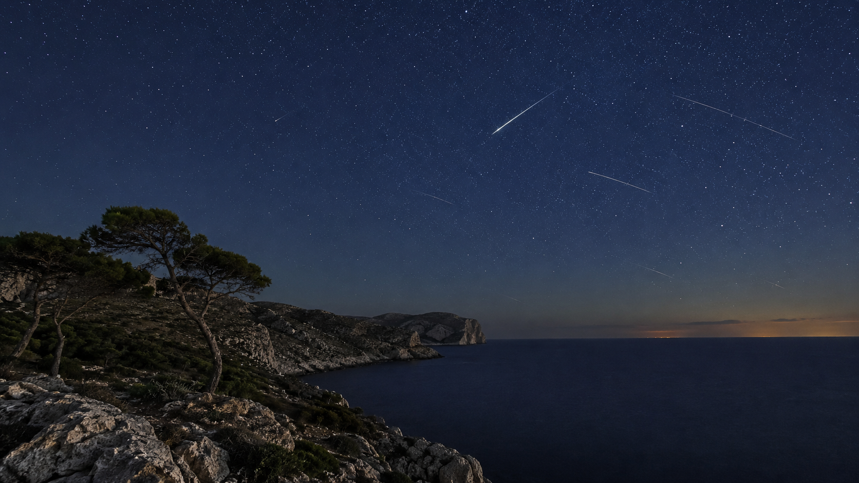Perseid meteors streak across a star-filled night sky above Mallorca’s rugged coastline and the Mediterranean Sea.